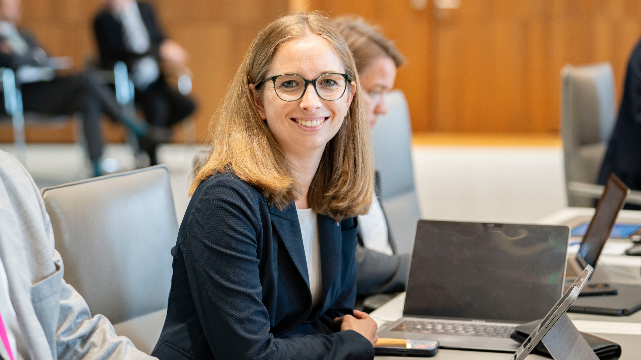 Anna Bauseneick sitzt im Plenarsaal des Niedersächsischen Landtages und schaut freundlich in die Kamera.